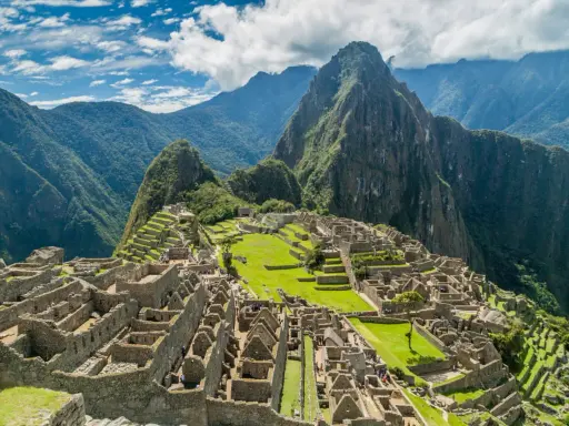 Machu Picchu, une des 7 merveilles du monde, se dresse majestueusement sur une crête montagneuse, entourée de verdure luxuriante et de nuages.